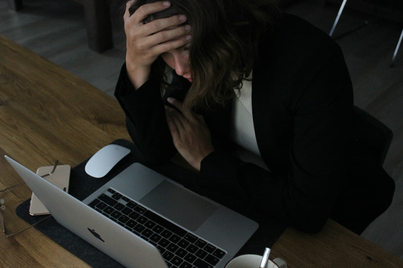 Une entrepreneuse dépassée, la tête dans les mains devant son ordinateur