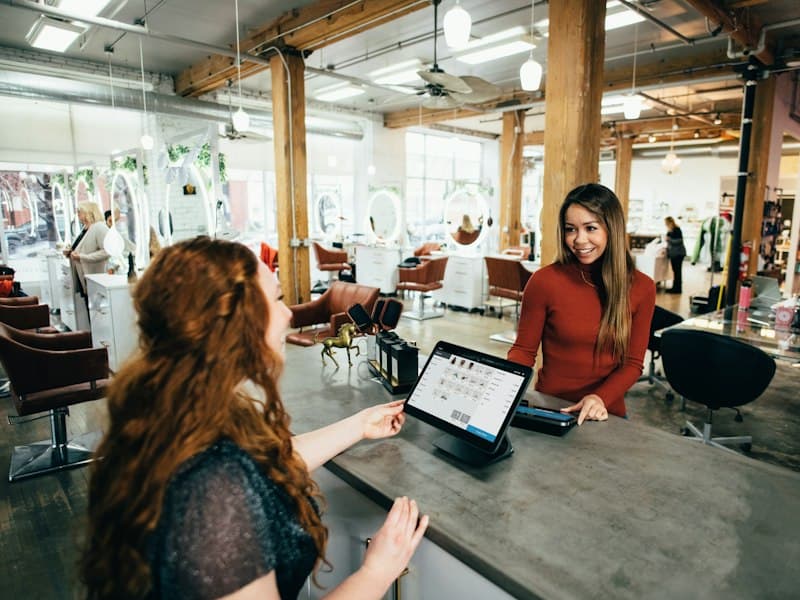 Une gérante de salon accueille une cliente avec sa tablette
